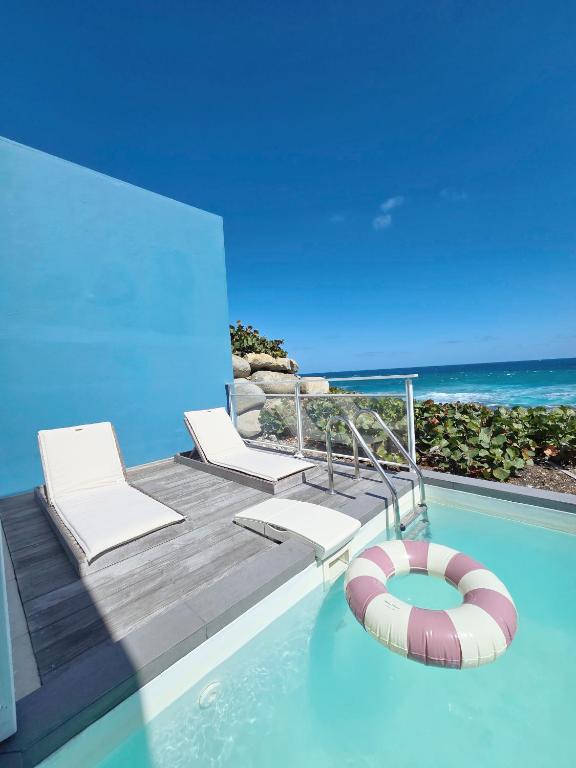 a swimming pool with two chairs and a beach at Villa Aura in Oyster Pond