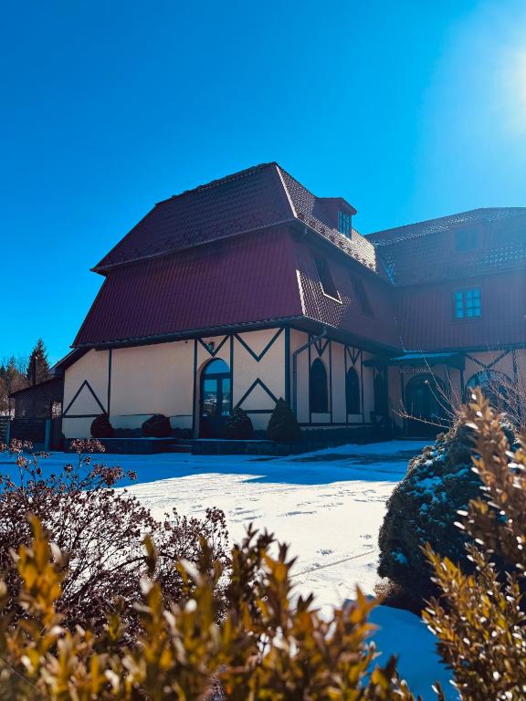 a large building with a red roof in the snow at Mohh prostir vidpochinky in Mohnate