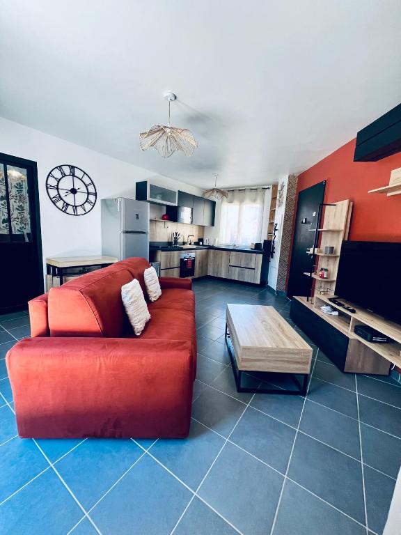 a living room with a red couch and a kitchen at L'Escale paisible in Gardanne