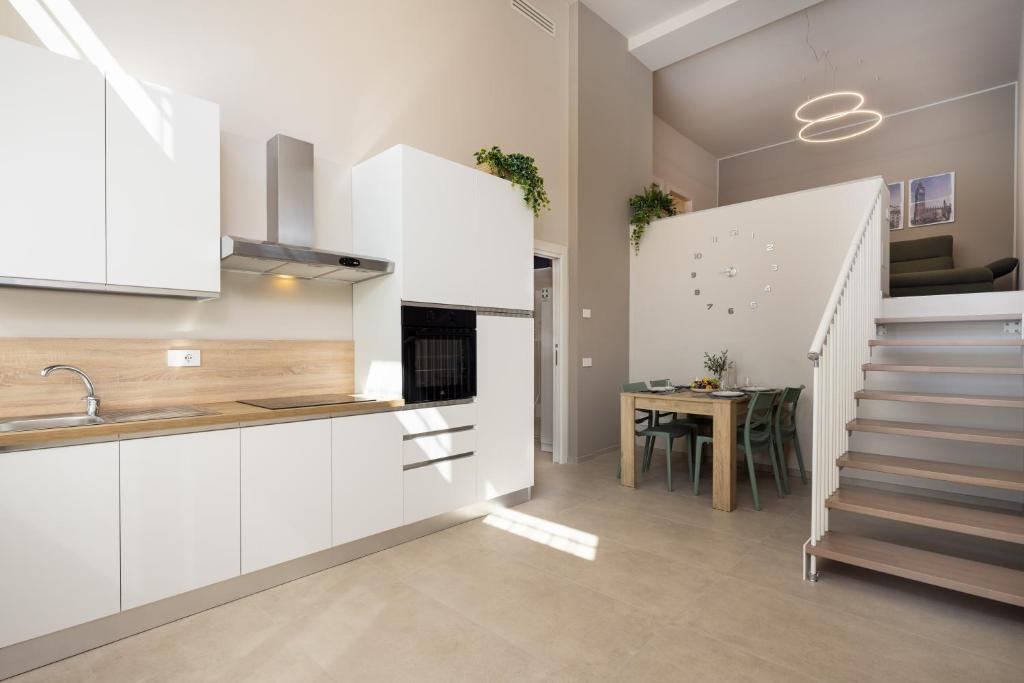 una cucina con mobili bianchi e una sala da pranzo con un tavolo di Casati47 a Magenta