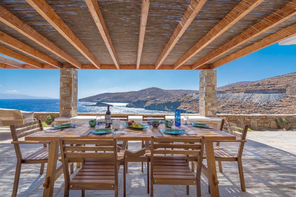 a wooden table and chairs on a patio with a view of the ocean at Ikos Kythnos in Kithnos