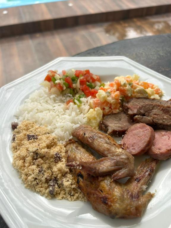 a plate of food with rice and meat and vegetables at Pousada Recanto Dos Pássaros in Colégio