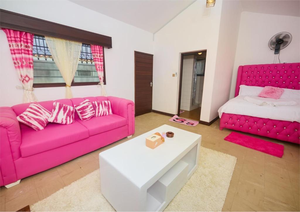 a living room with a pink couch and a bed at Cutie Studio Unit Nyali in Mombasa