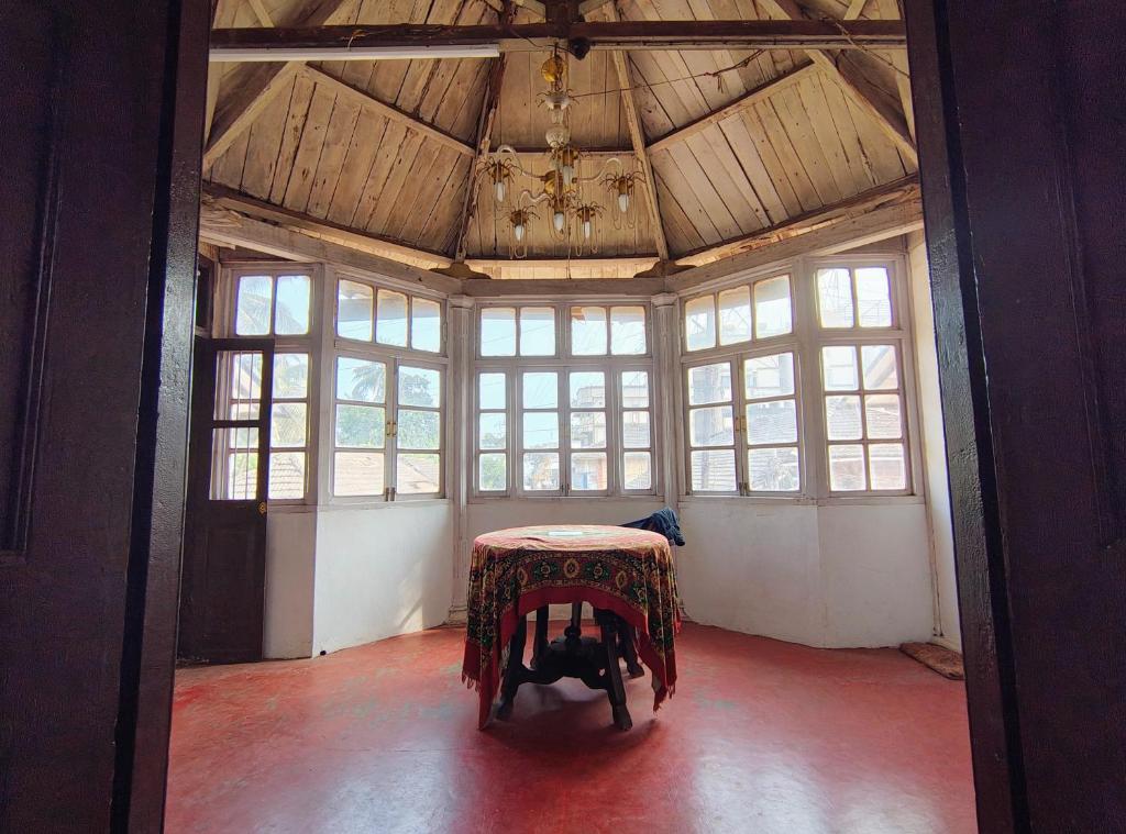 a room with a table in a room with windows at Vikram homestay in Malvan