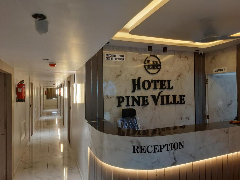 ein Hoteleingang mit einem „Hotel Pineville“-Schild an der Wand in der Unterkunft Hotel Pine Ville in Ahmedabad
