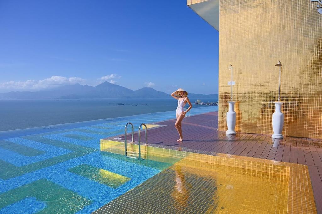 a woman standing on the edge of a swimming pool at Luxury Studio Infinity Pool Golden Bay in Danang