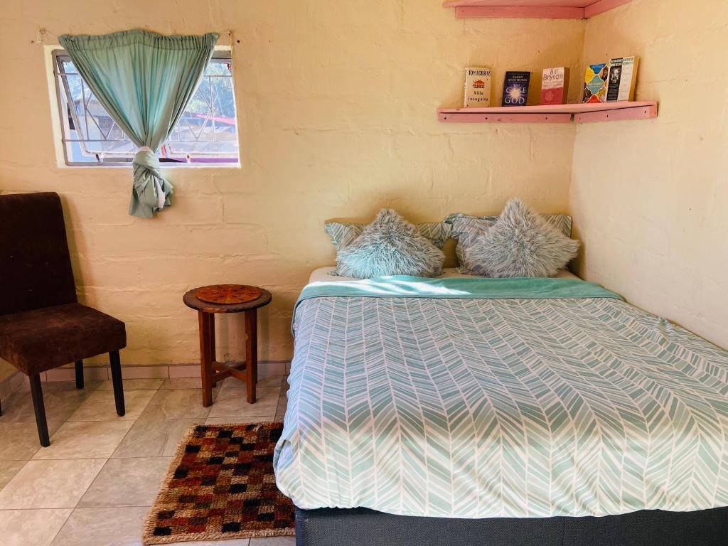 a bedroom with a bed and a chair and a window at Mountain View Escape in Mbabane