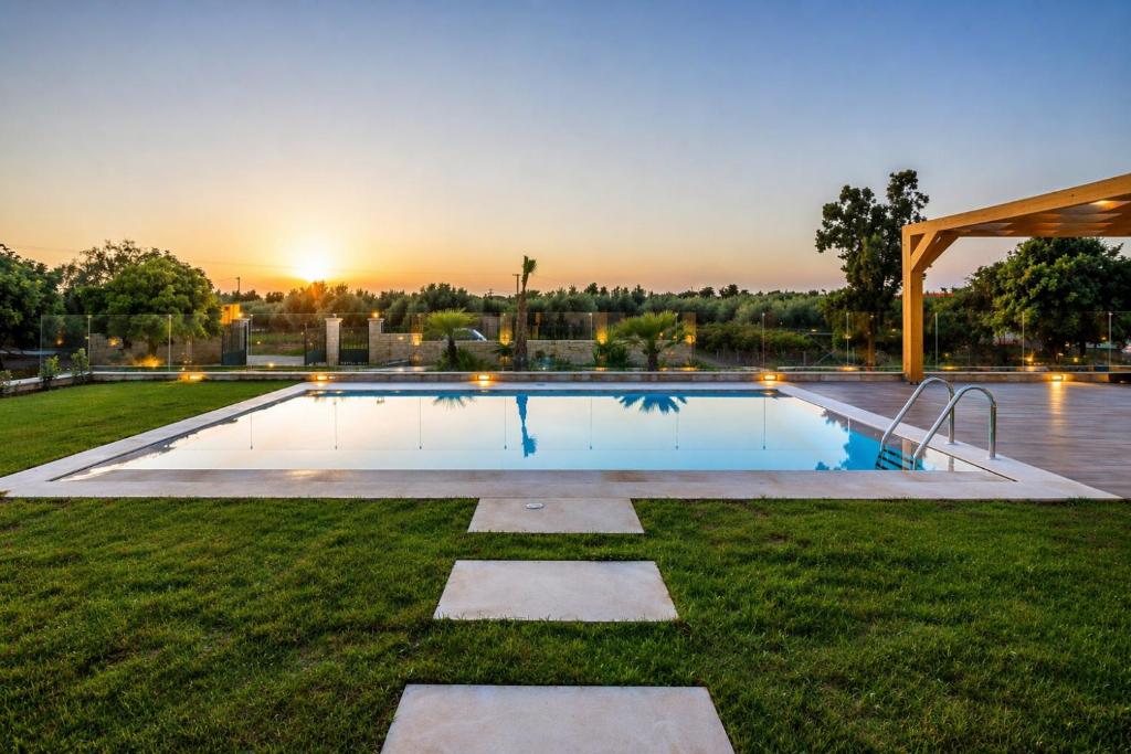 a swimming pool in a yard with a sunset in the background at Villa Sandi with Private Pool in Hersonissos