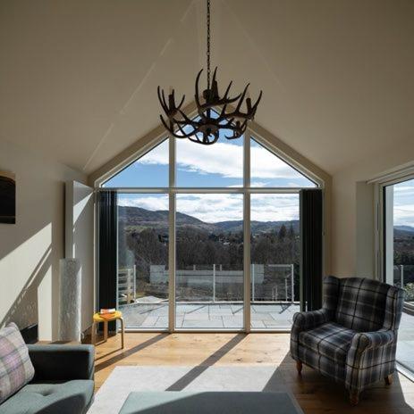a living room with a couch and a chandelier at Sunny Ridge in Fort Augustus