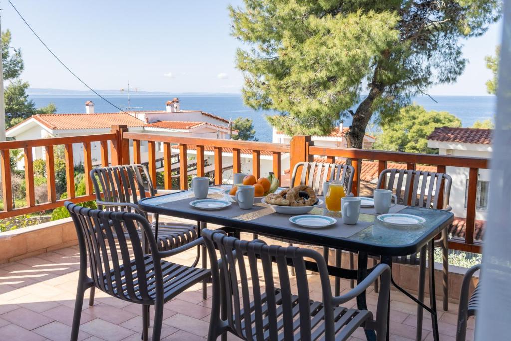a blue table and chairs on a balcony with the ocean at Sunset Cove by halu! - Spacious 4-bedroom Villa in Neos Marmaras