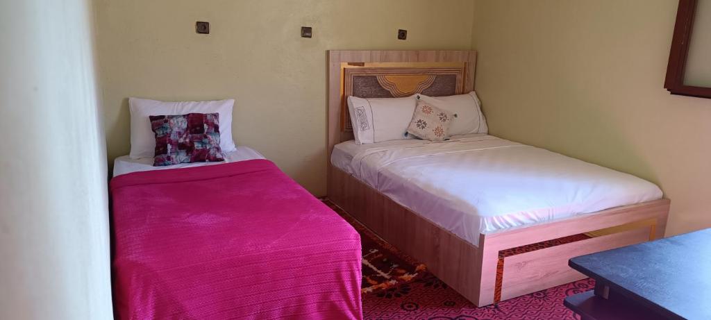 a small room with two beds with pink sheets at Diafat ISSIRIDEN in Tazrouft