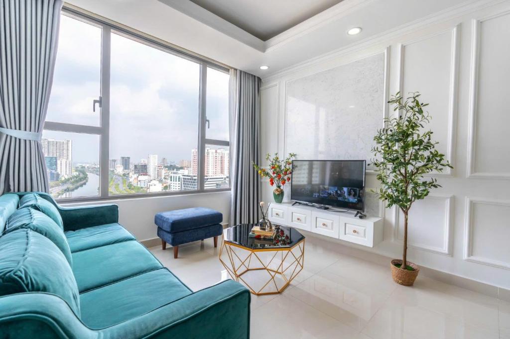 a living room with a blue couch and large windows at Apartment Luxury Center HCM City with Infinity Pool in Ho Chi Minh City