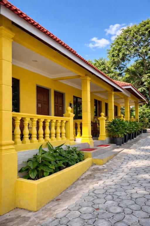 a yellow building with a fence and some plants at Fiqthya Chalet & Cafe in Tioman Island