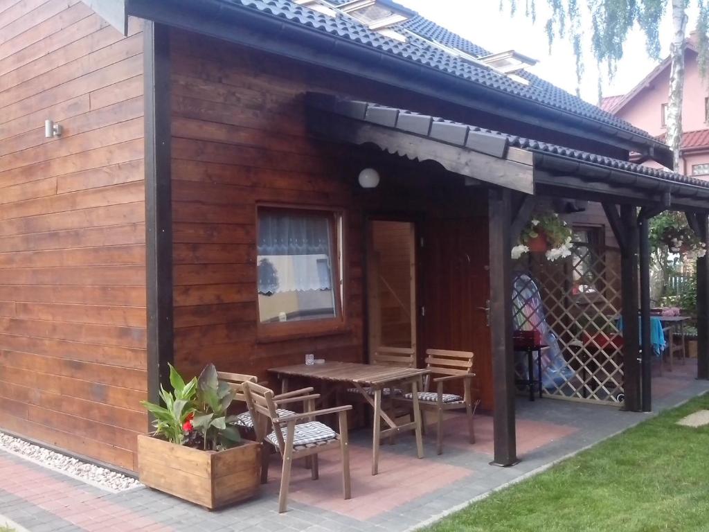 a wooden cabin with a table and chairs in a yard at Apartamenty Kompas in Międzywodzie