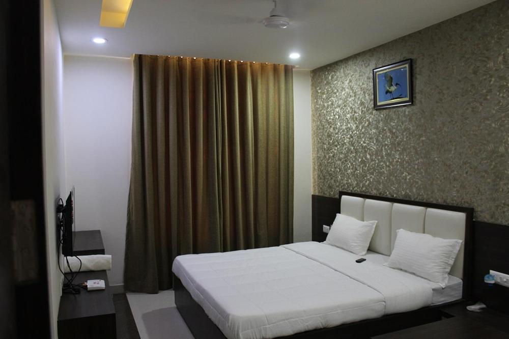 a bedroom with a bed with white sheets and a window at Hotel Celebration in Bharatpur