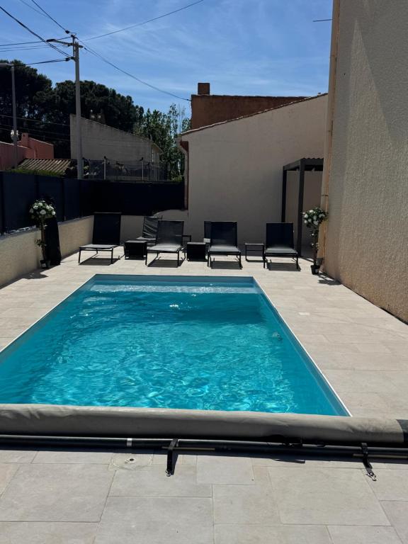 a swimming pool on a patio with chairs and a building at Piscine chauffée Clim WIFI 13 personnes Centre Valras-Plage in Valras-Plage