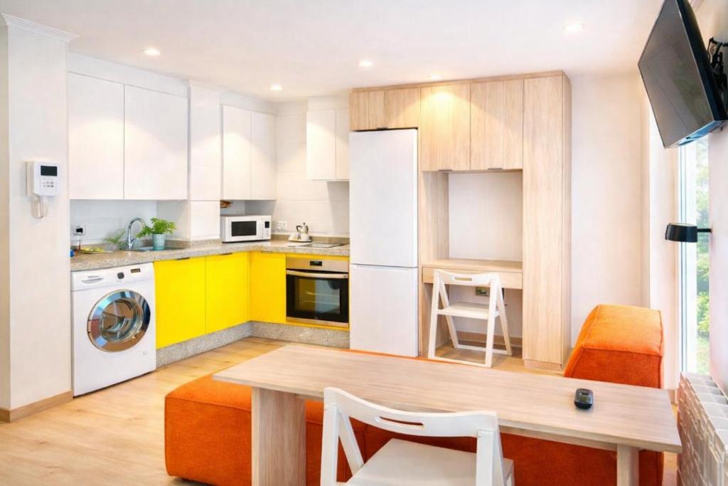 a kitchen with yellow and white cabinets and a table at Apartamentos 19 Living in León