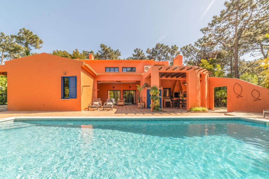 an orange house with a swimming pool in front of it at Villa Bambu in Charneca