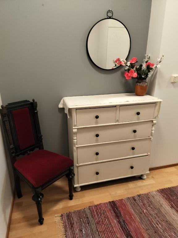 a white dresser with a mirror and a chair at Varakoti Helmi in Loimaa