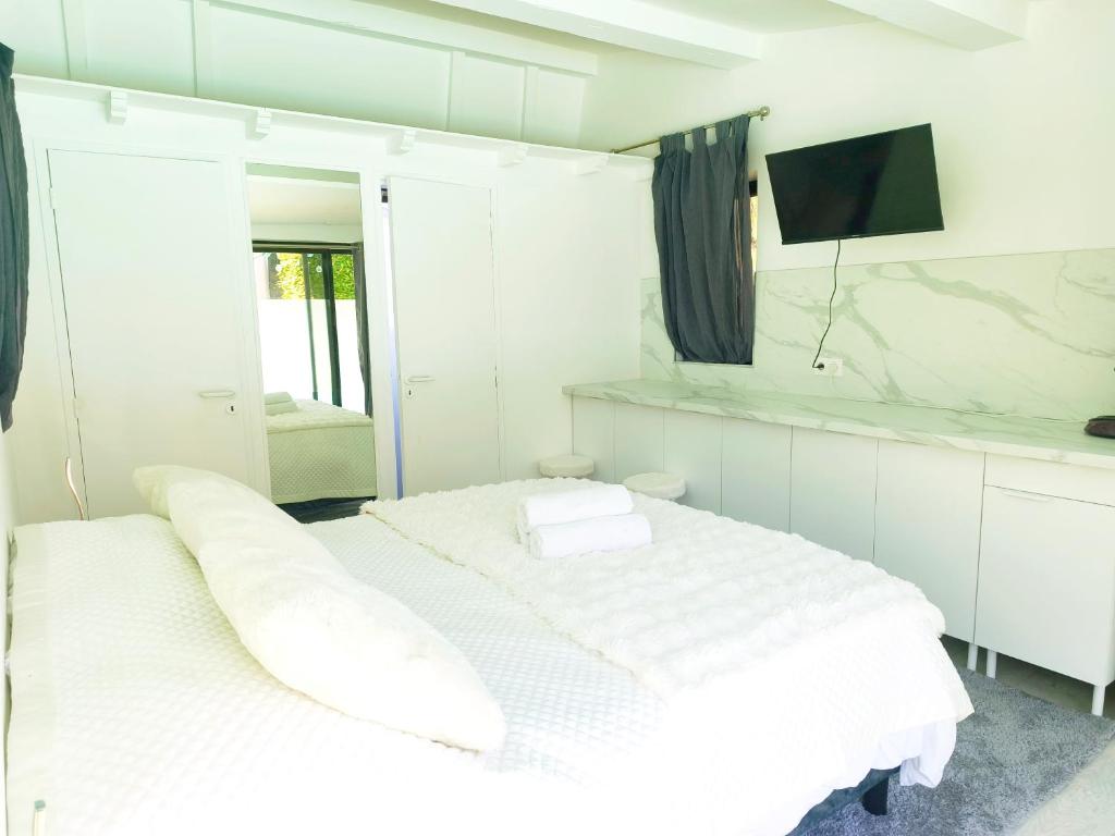 a white bedroom with two beds and a television at Coulounieix Resort in Coulounieix-Chamiers