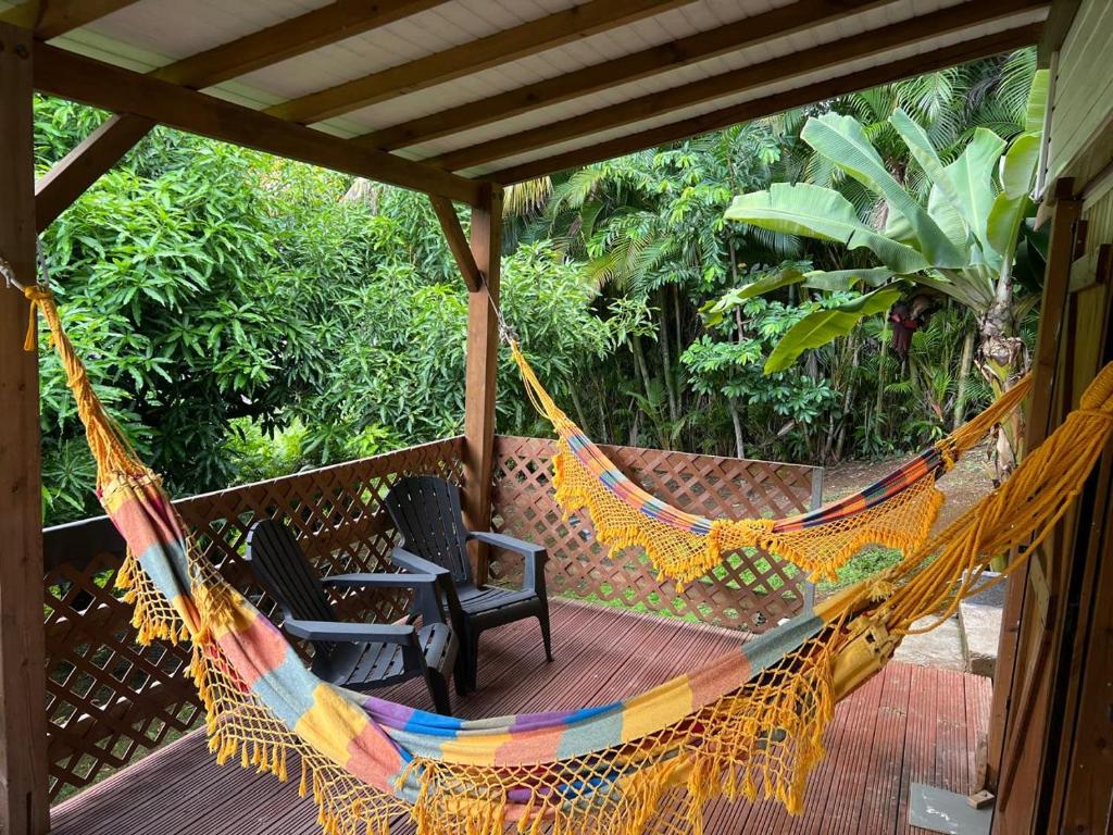 a hammock on a porch with two chairs at Coconut Studio in Capesterre-Belle-Eau