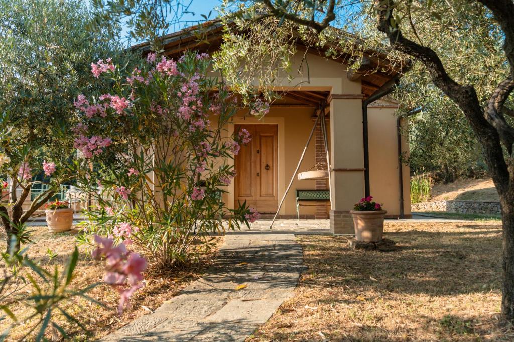 a house with a tree and flowers in front of it at Poggio del Raglio in Trequanda