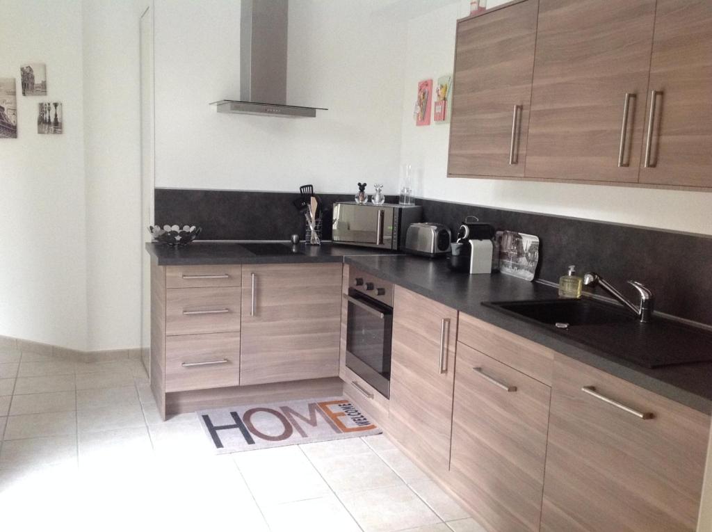 une cuisine avec des armoires en bois et un comptoir noir dans l'établissement Jardin&Terrasse Disneyland Paris, à Serris