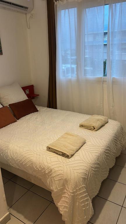 a bed with two towels on it with a window at Le Petit QG in Schœlcher