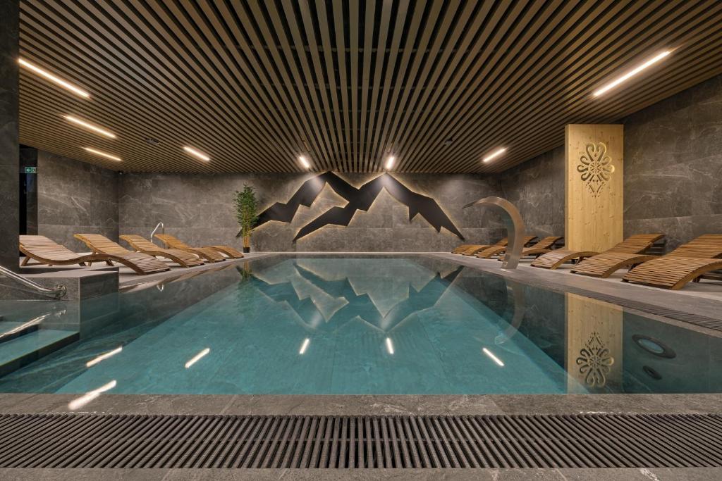 a swimming pool in a hotel with chairs and a swimming pool at BANIA BLACK MOUNTAIN I basen & spa in Białka Tatrzańska