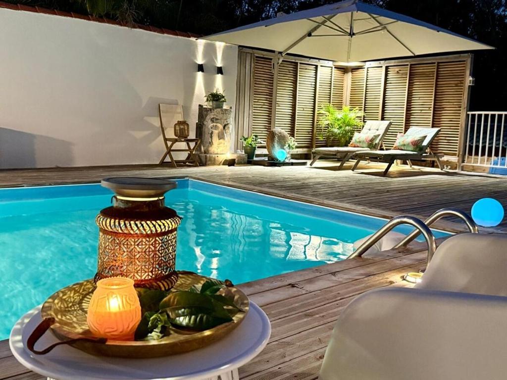 a table with a plate of food next to a pool at Villa Chic à Petit-Havre in Le Gosier