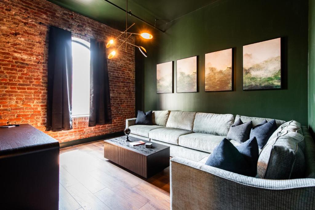a living room with a couch and a brick wall at Hollyhock Suite 505 in Louisville