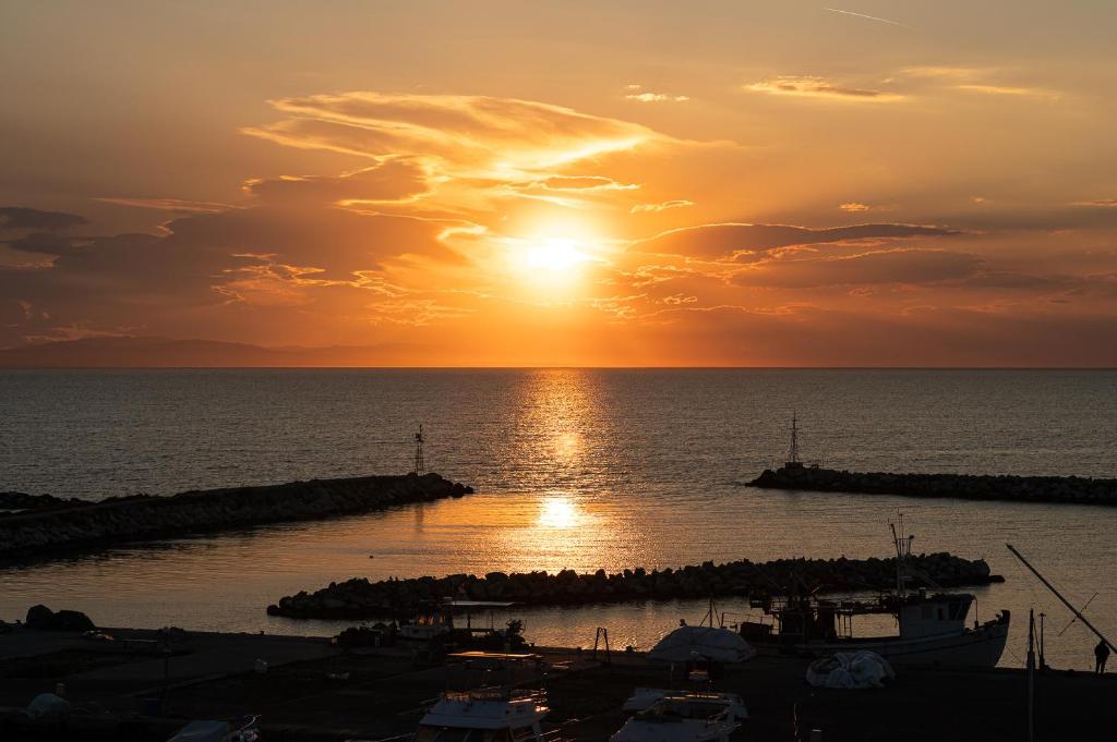 a sunset over the water with boats in a harbor at Delfini Girni Apartments in Paralia Katerinis