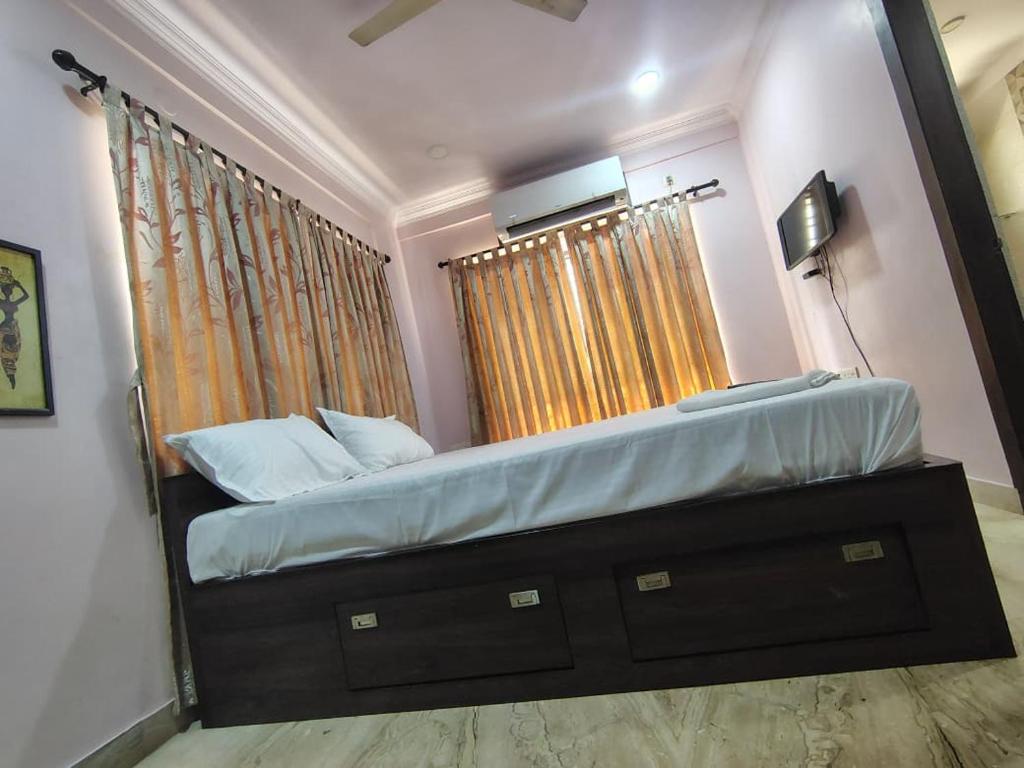 a bedroom with a bed with a dresser and two windows at Star Spandan in New Town