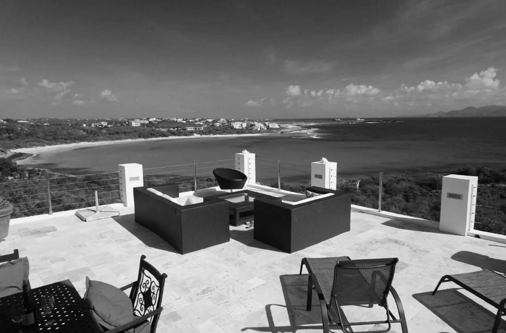 a patio with chairs and a table and a beach at Spectacular views in Long Path
