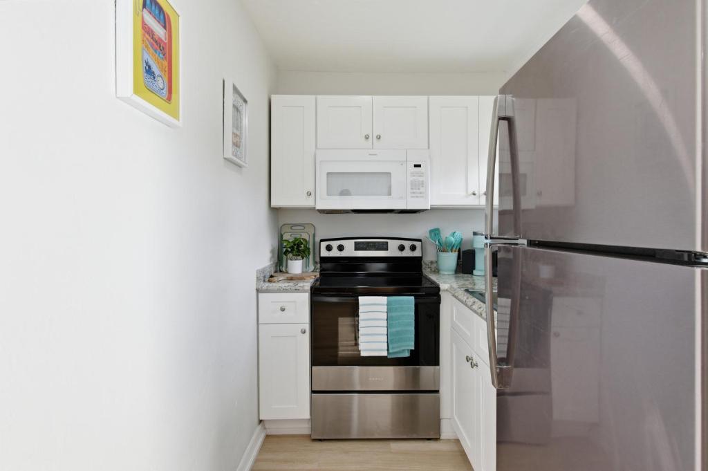 a kitchen with white cabinets and a stainless steel refrigerator at Naples Triplex Retreat in Naples