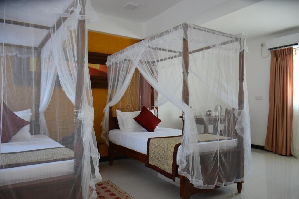 a bedroom with two beds with mosquito nets at Meili Lanka City Hotel in Kandy