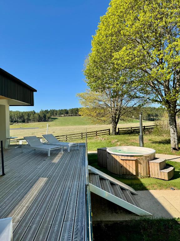 a deck with a bench and a table and trees at Domaine de Mende Brenoux Suites & SPA in Mende