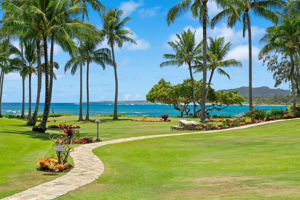 a golf course with palm trees and the ocean at Beachfront Lae Nani 3BD Condo AC & Heated Pool in Kapaa