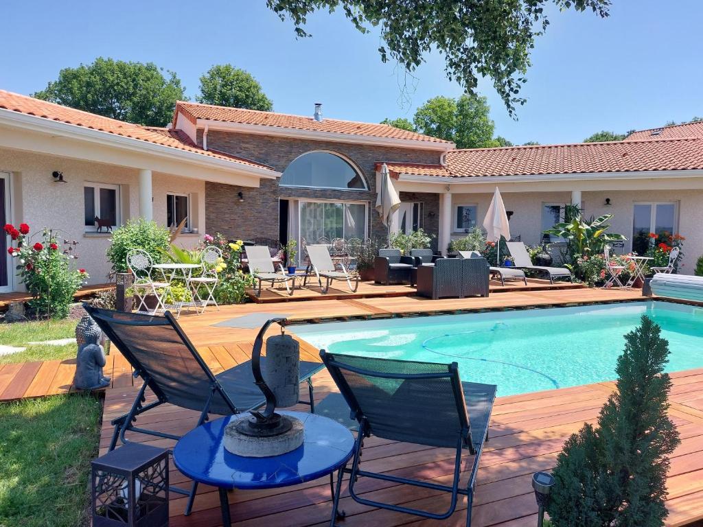 a swimming pool with chairs and a house at La Clef Des Anges 2 Chambres in Égliseneuve-près-Billom