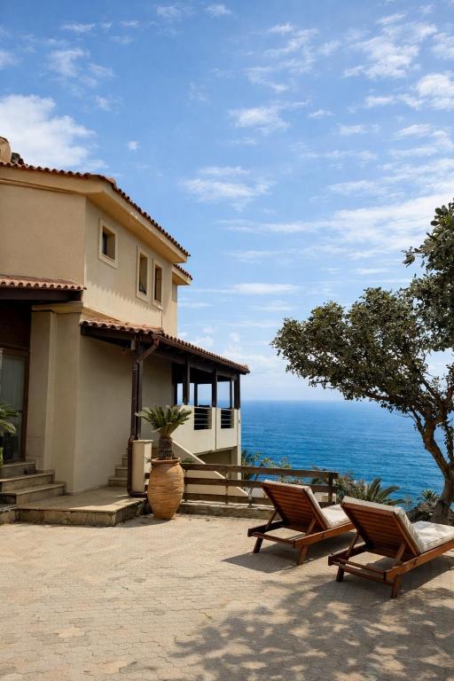 a house with two chairs in front of the ocean at Vitamin Sea Luxury Villas in Agia Pelagia