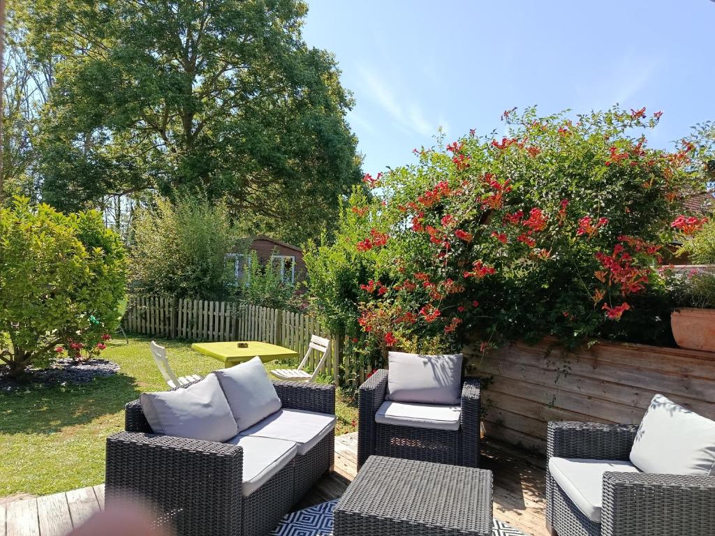 a patio with chairs and a table and flowers at les pins in Quend