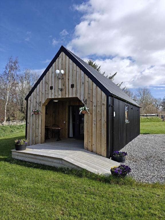 a large wooden building with a porch in a field at Pleasant Point Holiday Cottages in Glenurguhart