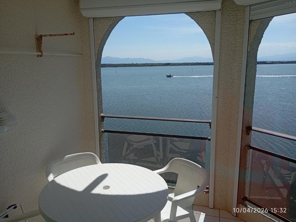 a table and chairs on a balcony with a view of the water at les pieds dans l'eau 1-Piscine chauffée in Le Barcarès