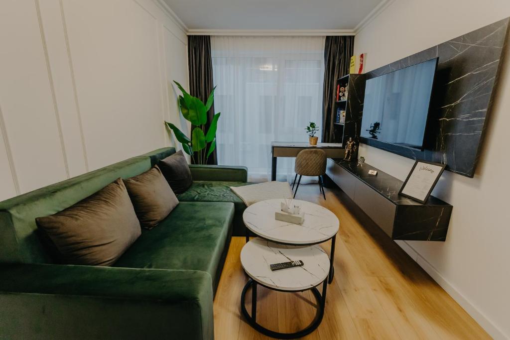 a living room with a green couch and two tables at Lumea Noir - Designer Apartment in Timișoara in Timişoara