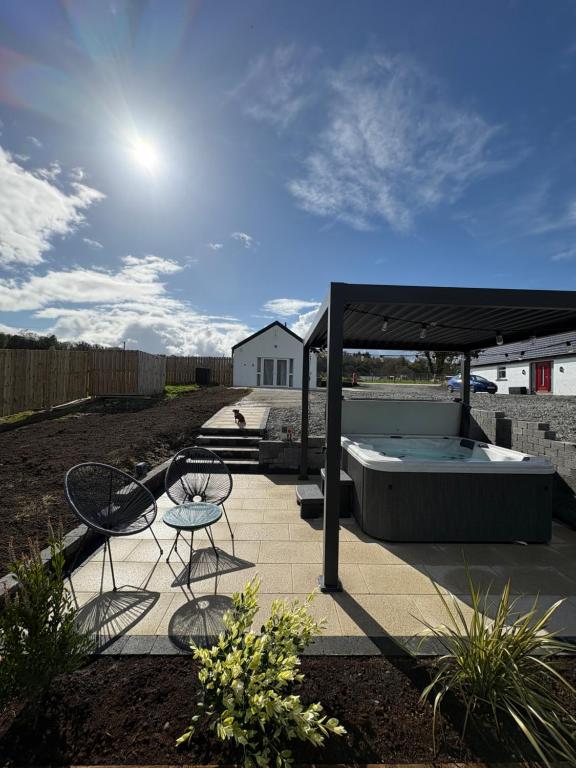 a patio with a hot tub and two chairs at The Bleach Green Cottage in Drumahoe