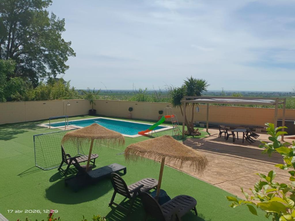 a swimming pool with chairs and umbrellas and a playground at Villavera in Villaverde del Río