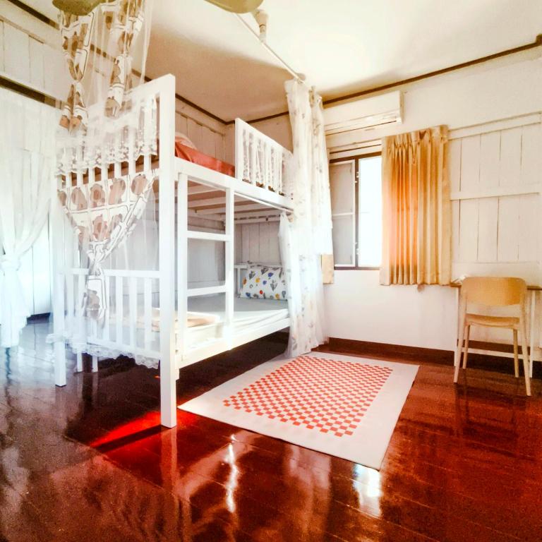 a bedroom with a white bunk bed with a red rug at NiranHouse Hostel in Sathani Phitsanulok