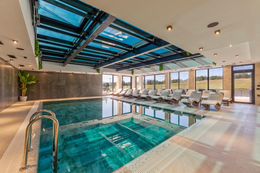 a swimming pool with chairs and a table in a building at Villa Di Montagna wellness & spa in Zlatibor
