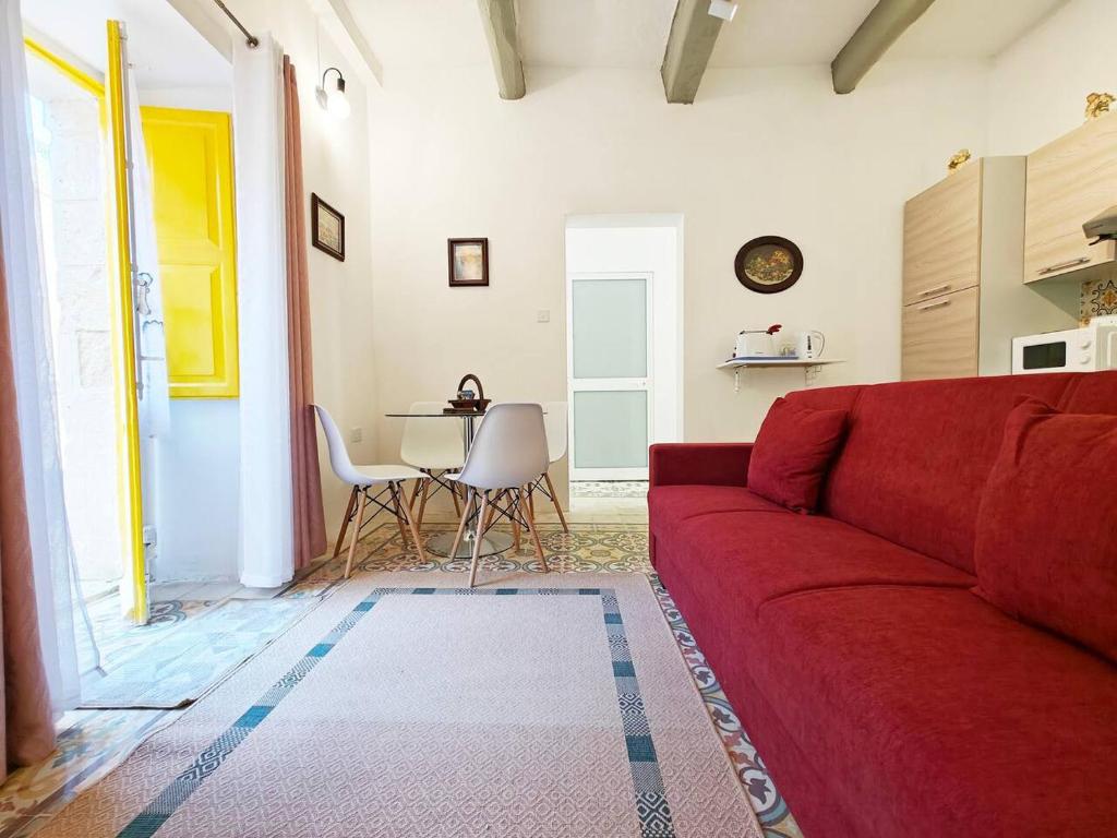 a living room with a red couch and a table at Dar Marija in Valletta