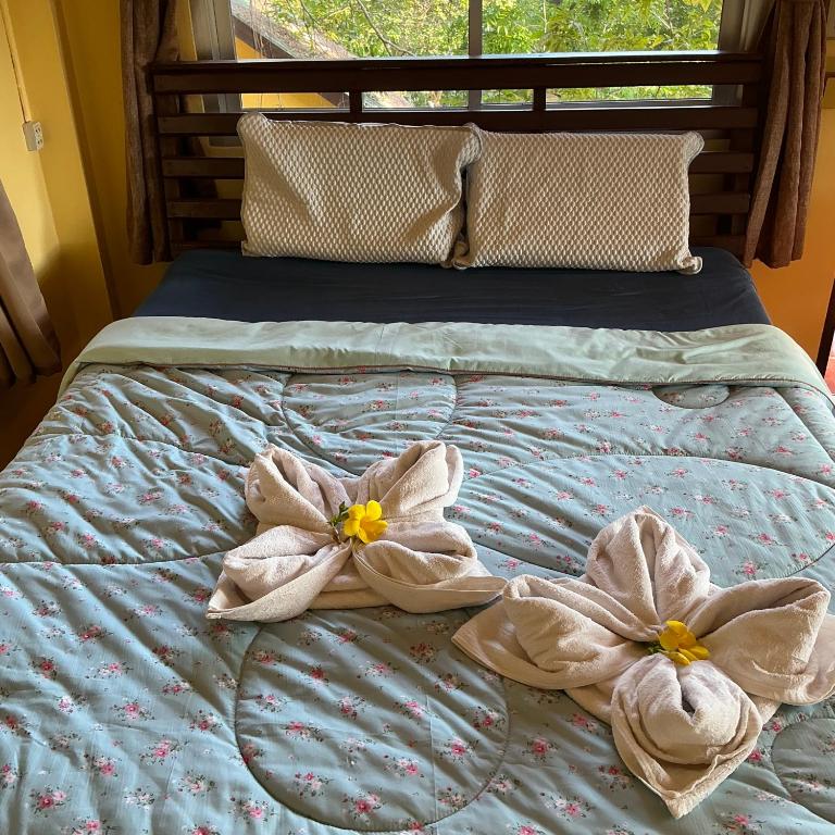 two towels on a bed with flowers on it at Elephant garden2 in Trat